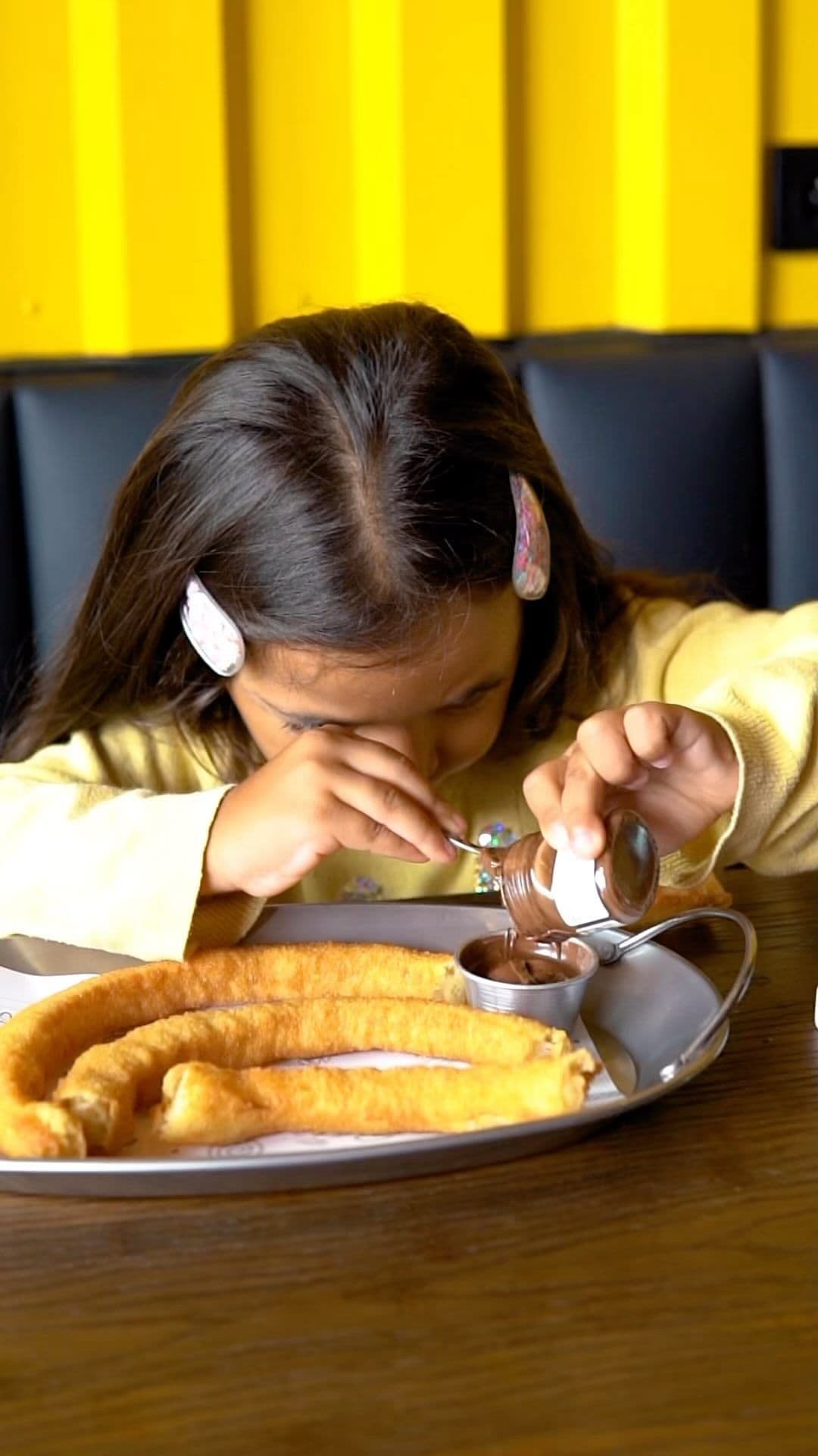 Salle de Churros & Company — mur jaune signature et banquettes